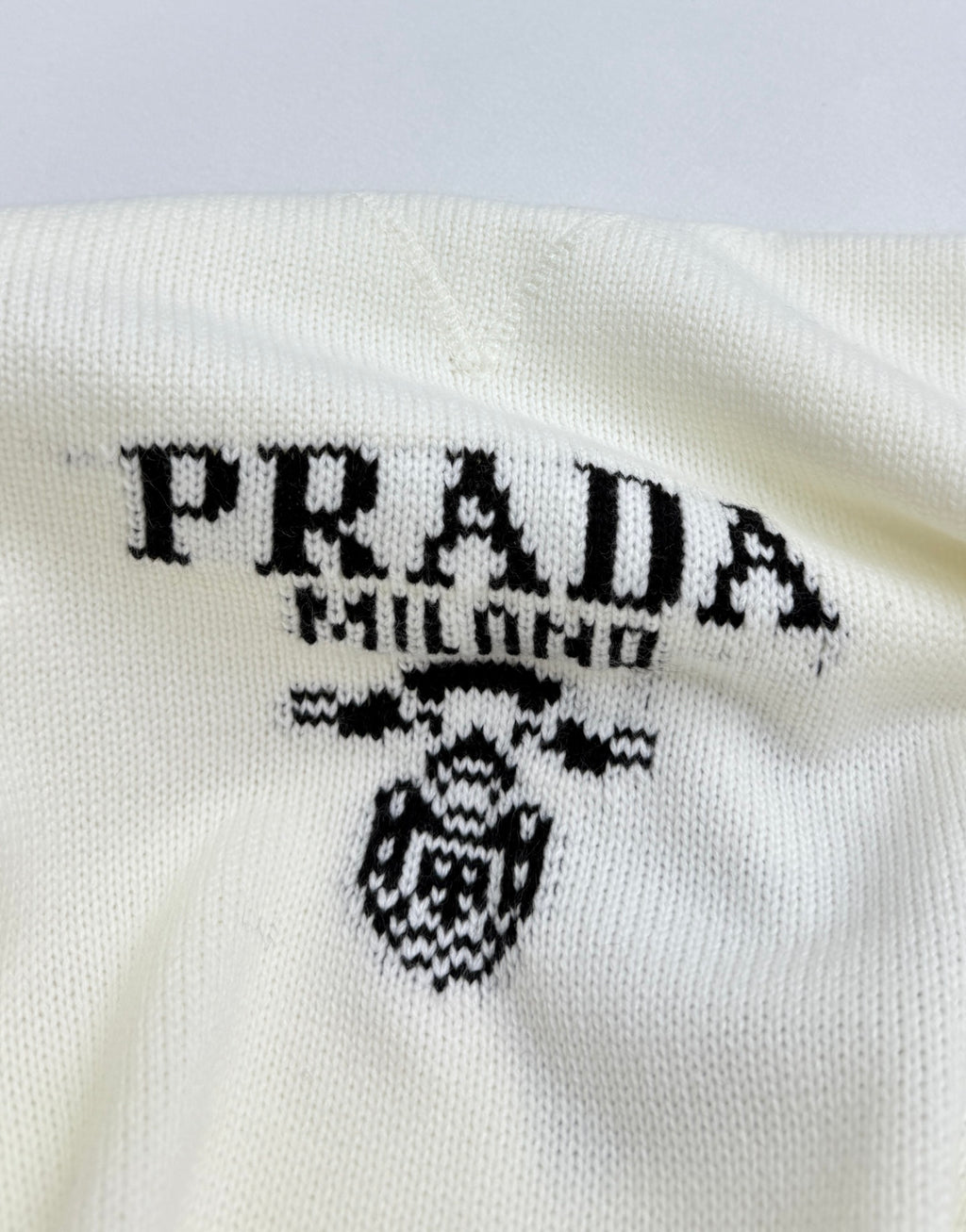 PRADA Milano logo graphic and crest on pale knit sweater front