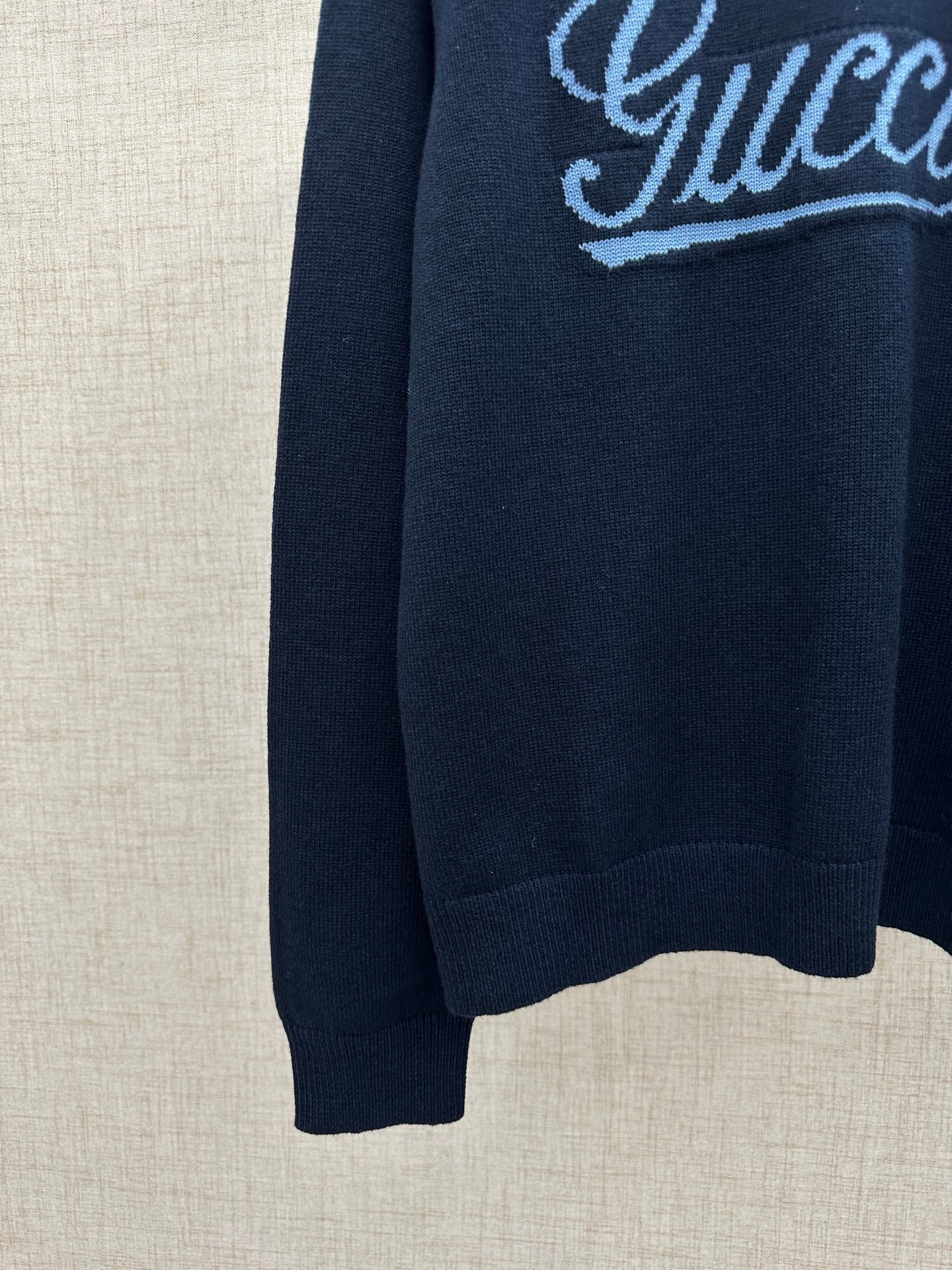 Navy knit sweater with embroidered 'Gucci' script near shoulder