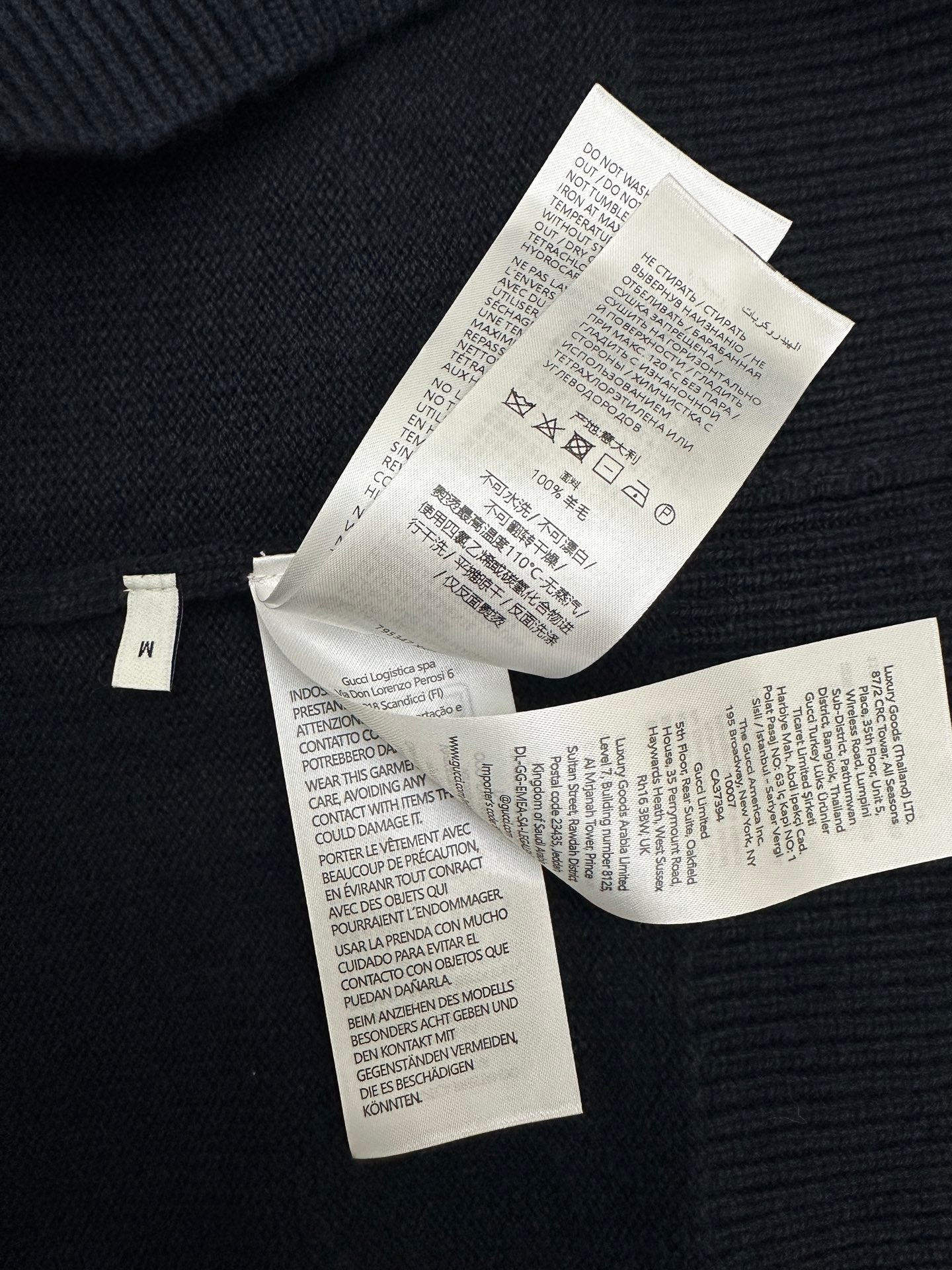Black knit sweater with multiple white size and care labels