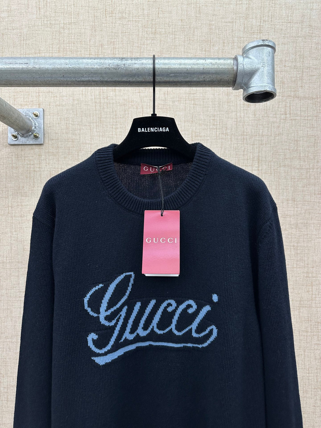 Navy knit sweater with large 'Gucci' script logo and hanging price tag
