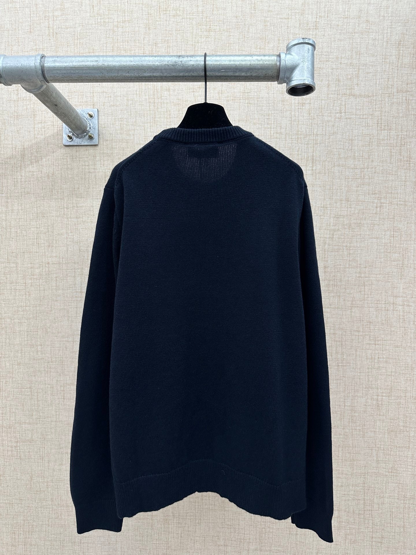 Navy knit sweater with ribbed crew neckline and relaxed back hem