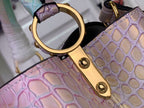 Louis Vuitton handbag detail: gold-tone D-ring and strap hardware on croc-textured pastel leather