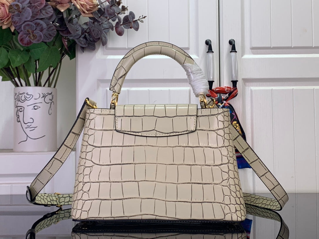 Light beige croc-embossed handbag with curved top handle and shoulder strap.