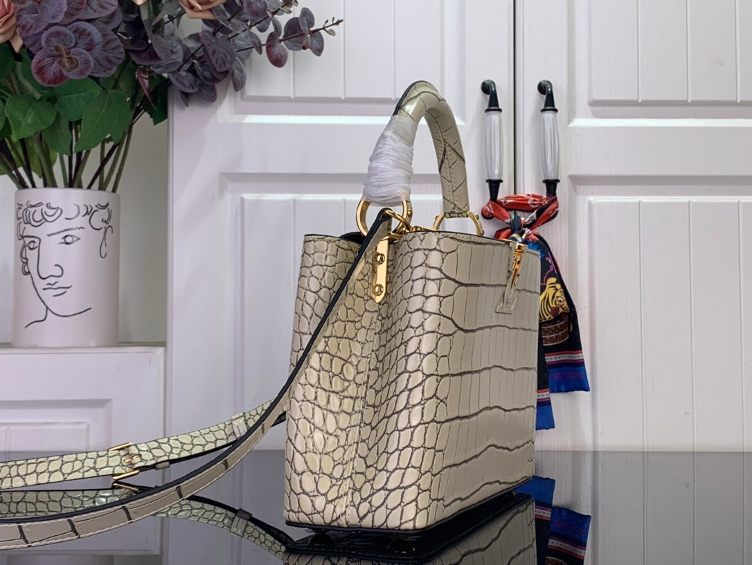 Light beige croc-embossed handbag with adjustable shoulder strap and gold hardware.