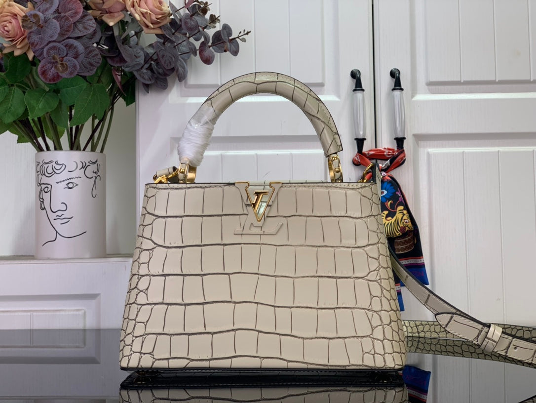 Louis Vuitton croc-embossed light beige handbag with top handle and gold LV clasp.
