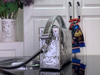 Louis Vuitton silver monogram handbag side view with top handle and shoulder strap