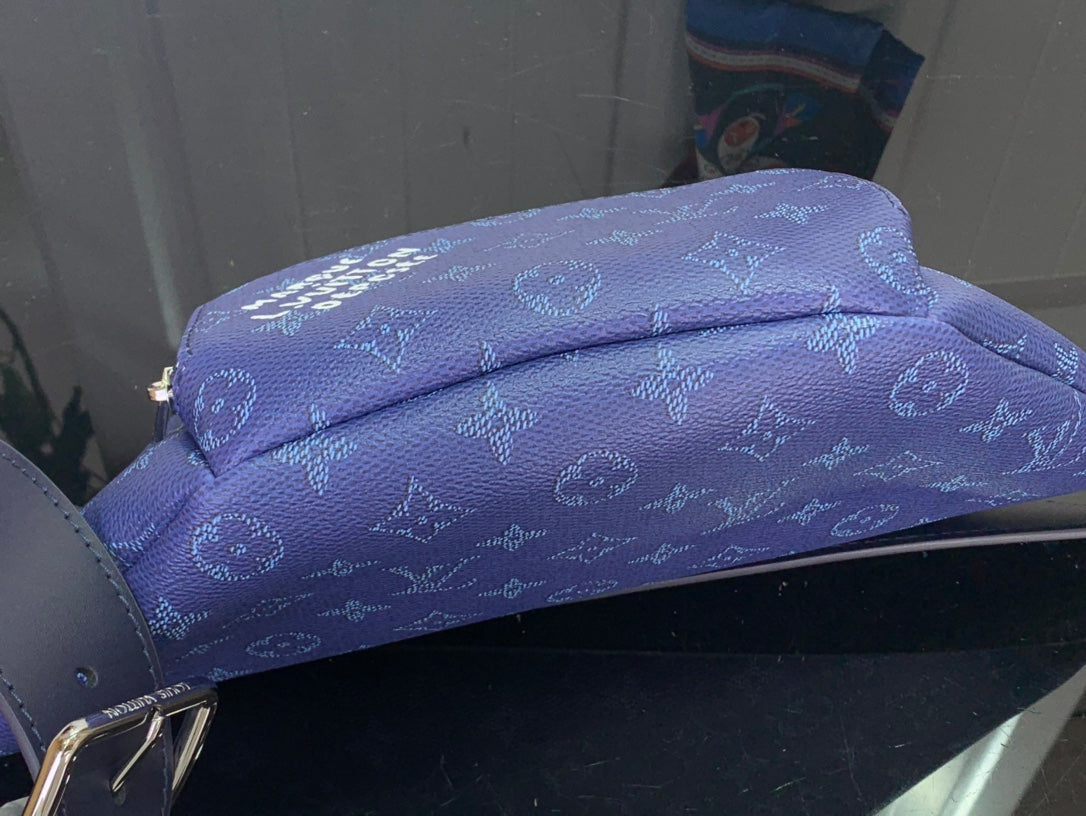 Blue monogram fabric flap with layered fold and stitched trim detail