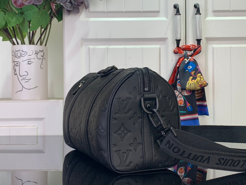 Dark monogram cylindrical duffel bag with zip closure and shoulder strap