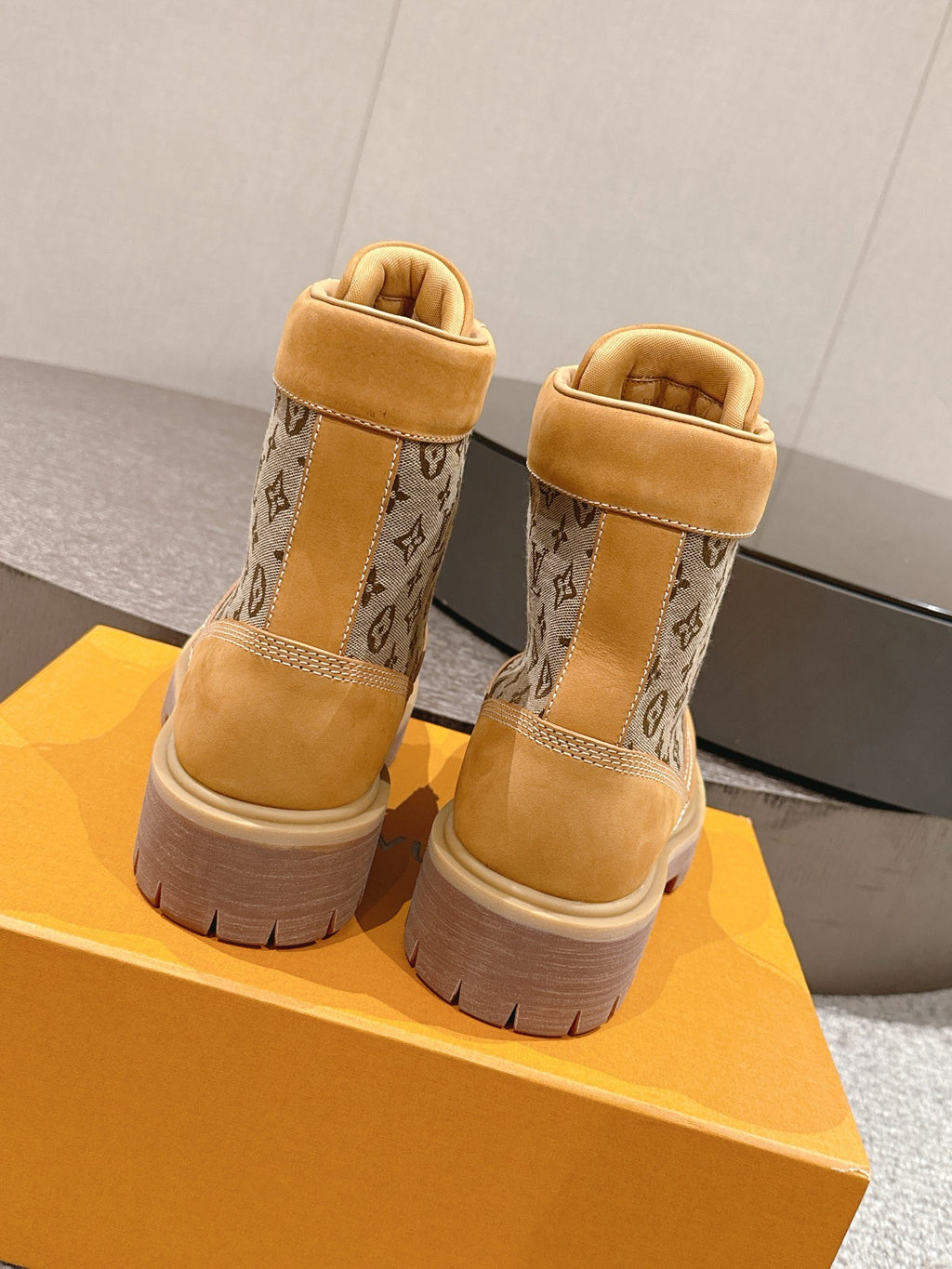 Back view of tan lace-up ankle boots with monogram fabric panels and chunky sole