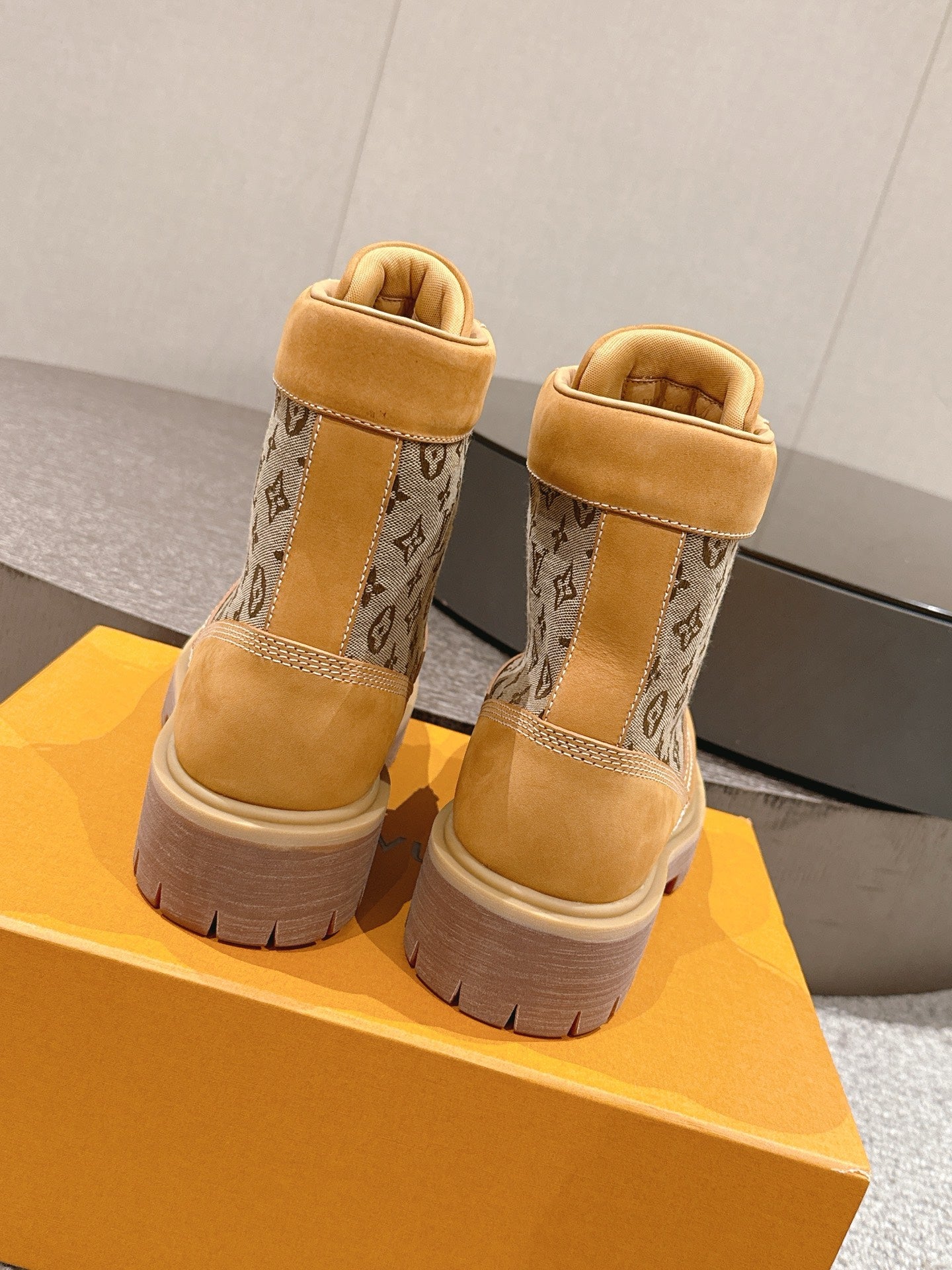 Back view of tan lace-up ankle boots with monogram fabric panels and chunky sole