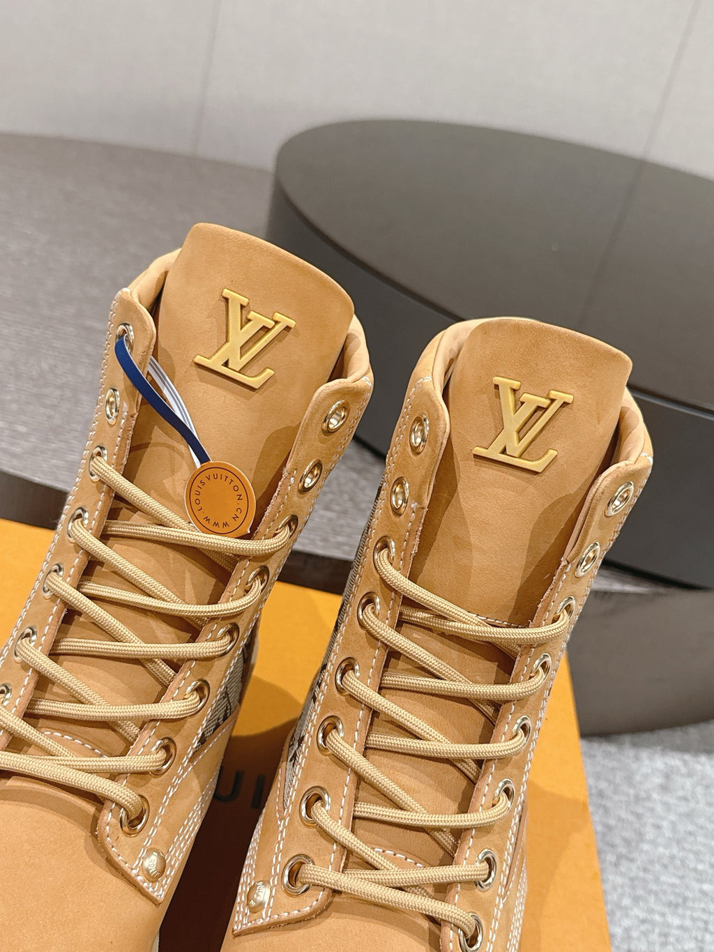 Close-up of tan lace-up ankle boots with LV logo on tongue and monogram side trim
