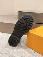 Black boot outsole with patterned tread and embossed circular logo