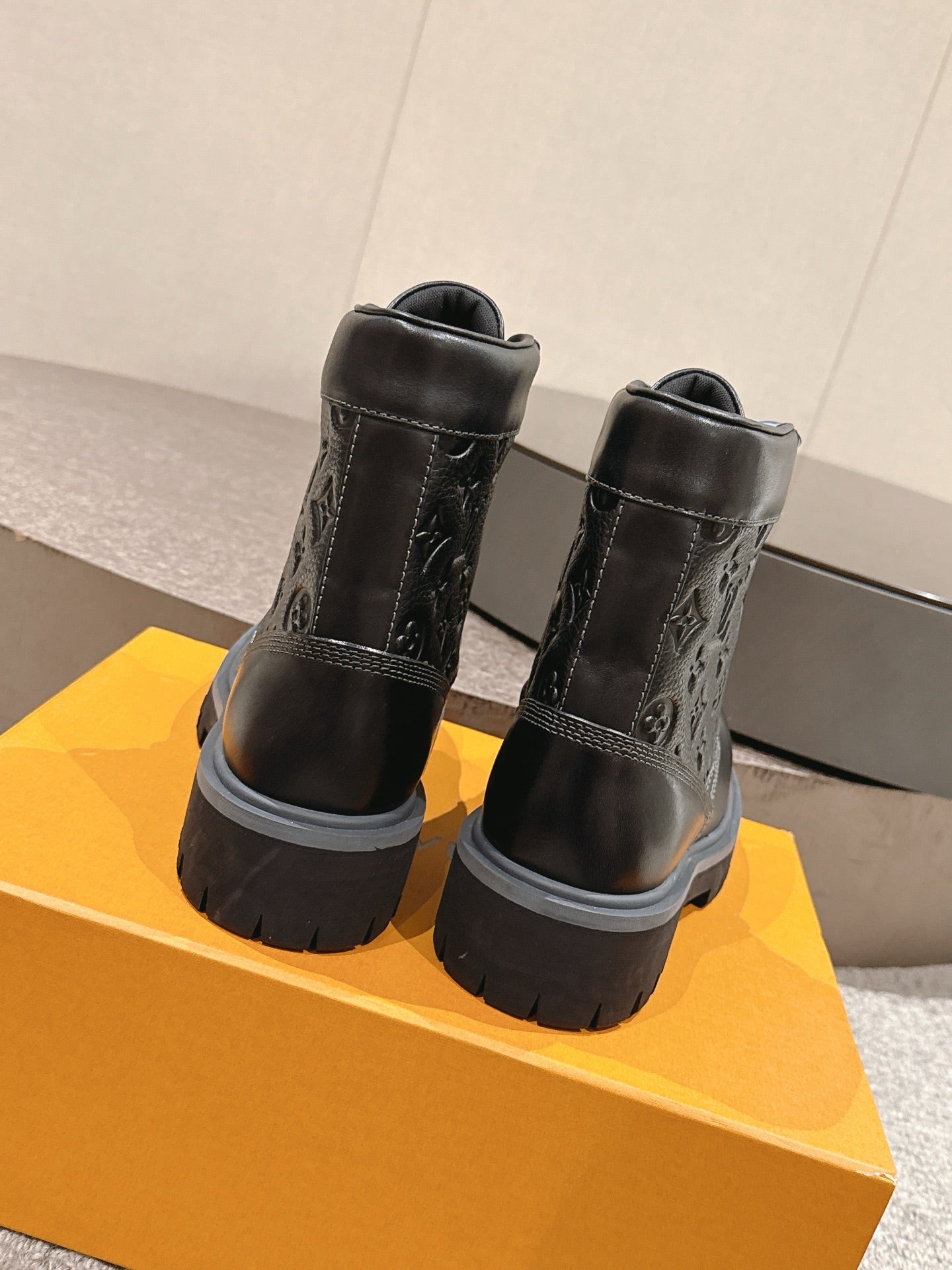 Black ankle boots with monogram embossing, rear view, chunky tread sole