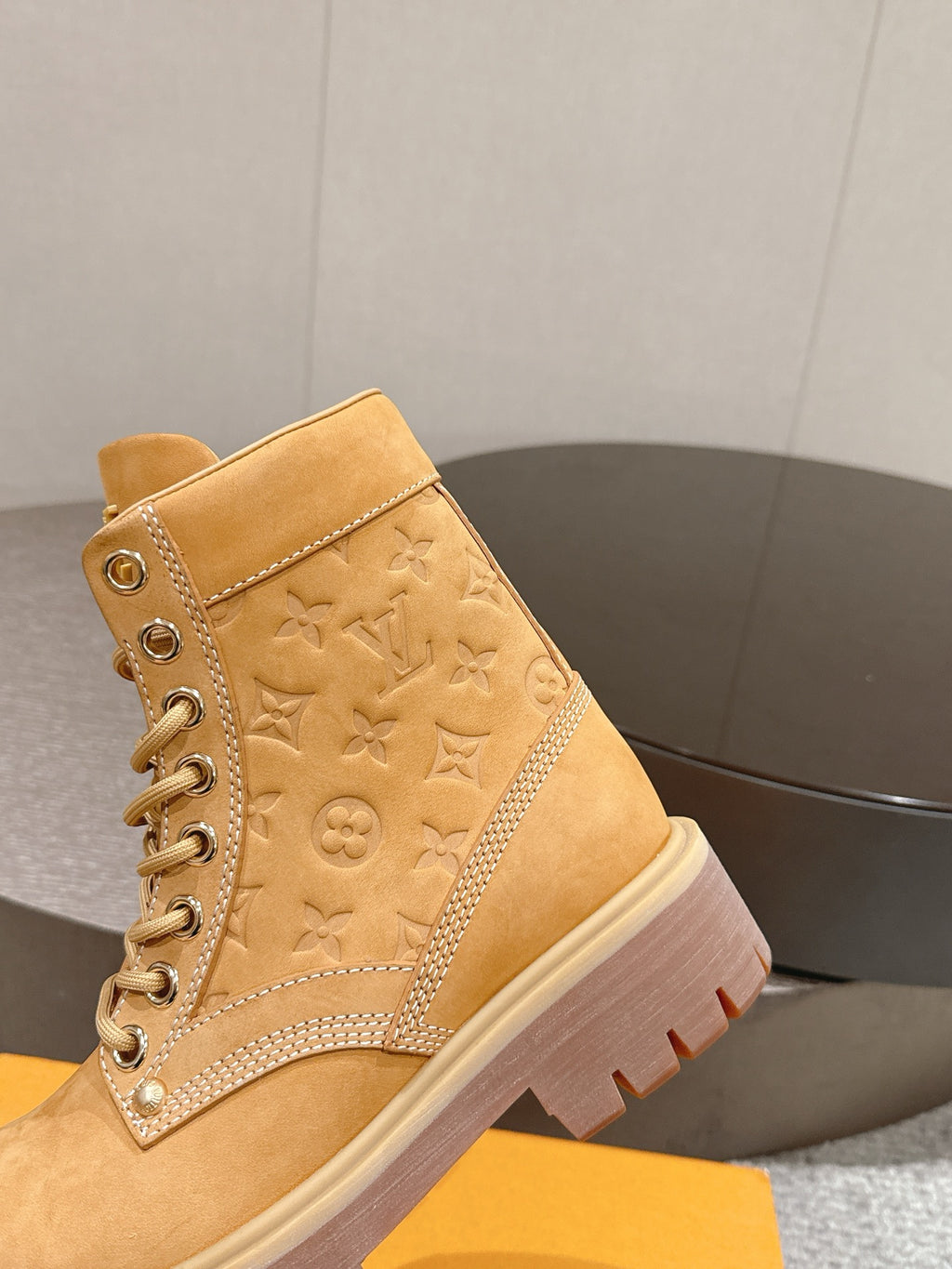 Tan suede lace-up ankle boot with embossed monogram pattern and rubber outsole