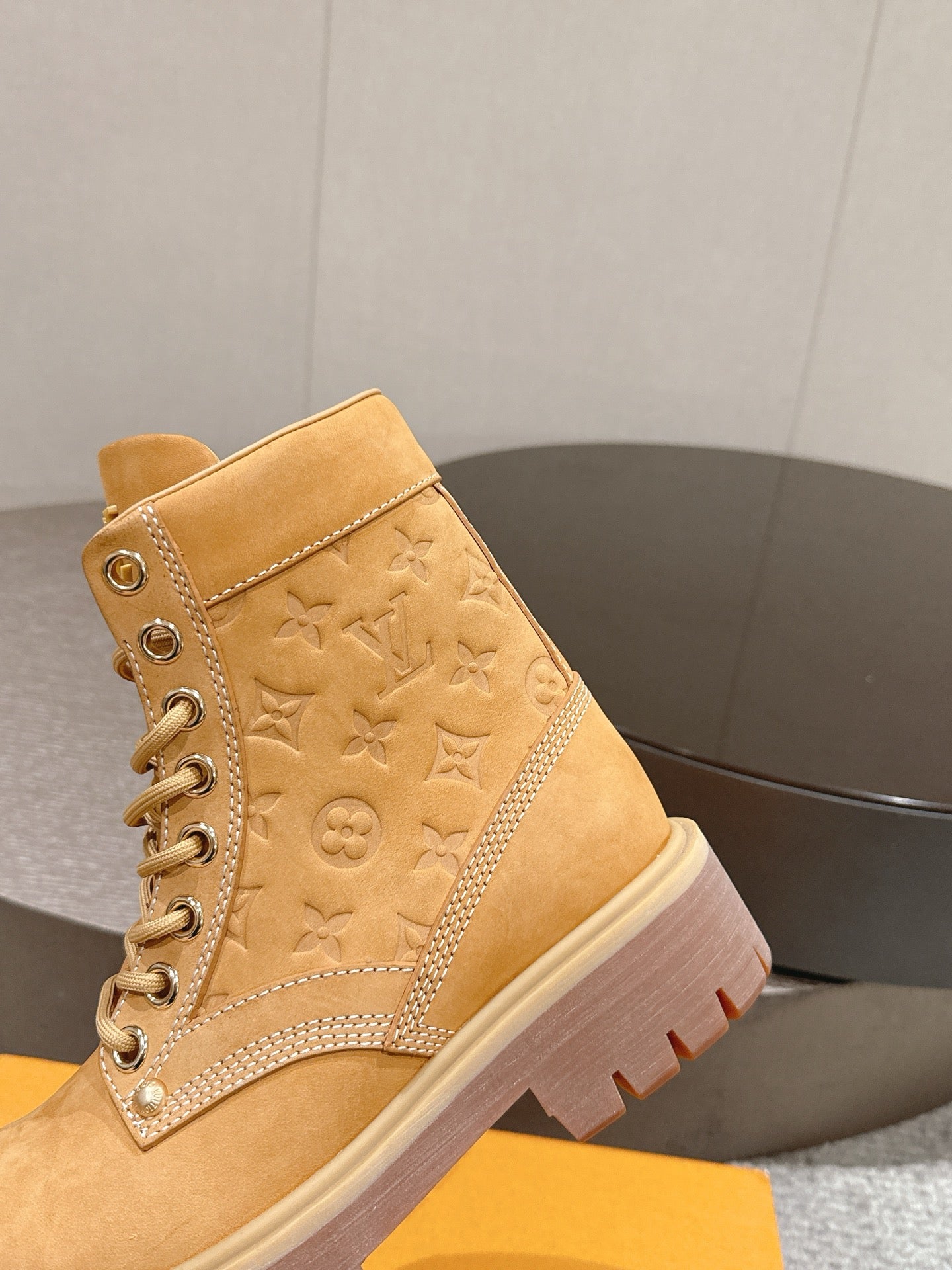 Tan suede lace-up ankle boot with embossed monogram pattern and rubber outsole