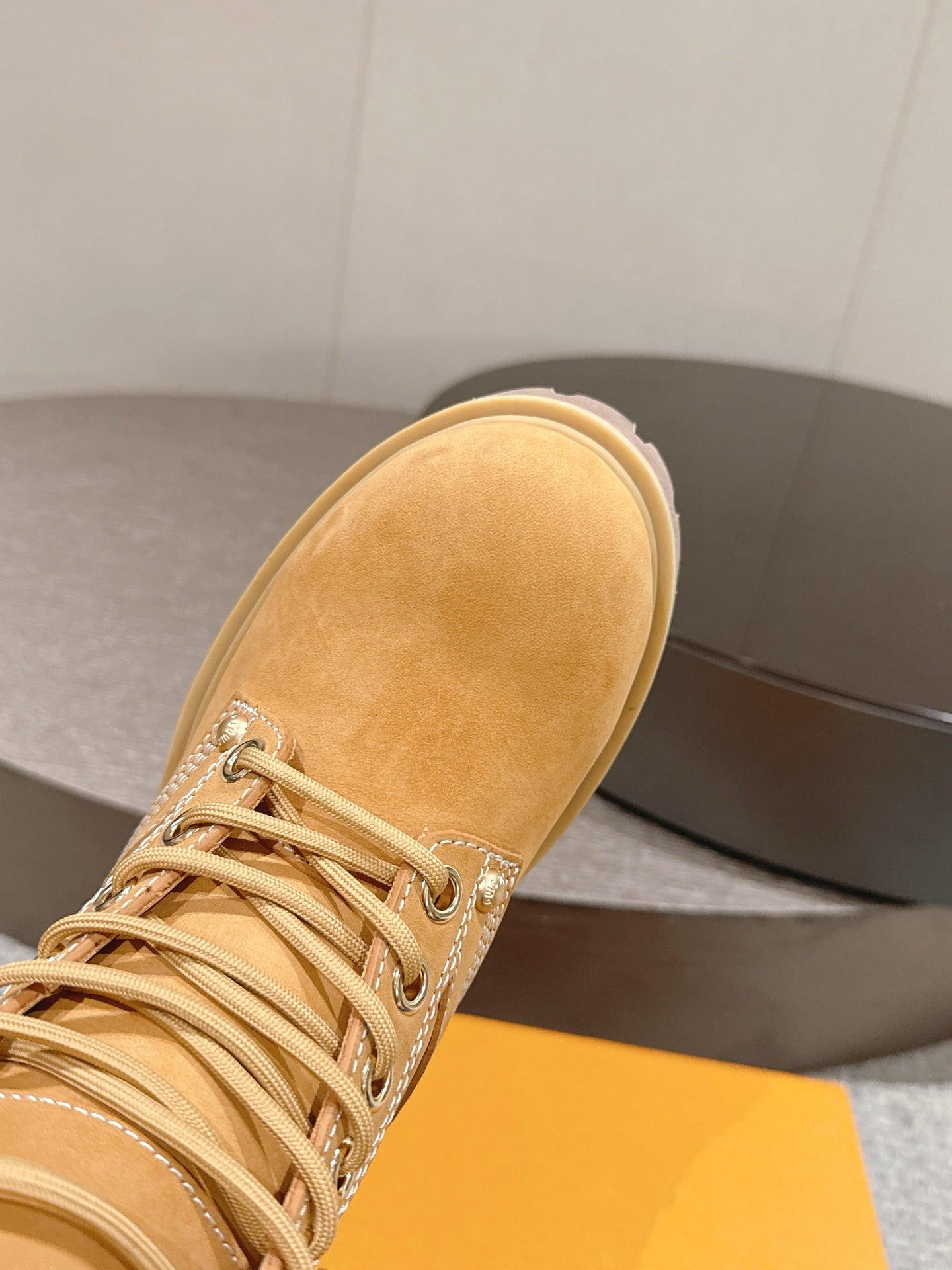 Tan suede lace-up ankle boot close-up, showing textured upper and stitching detail