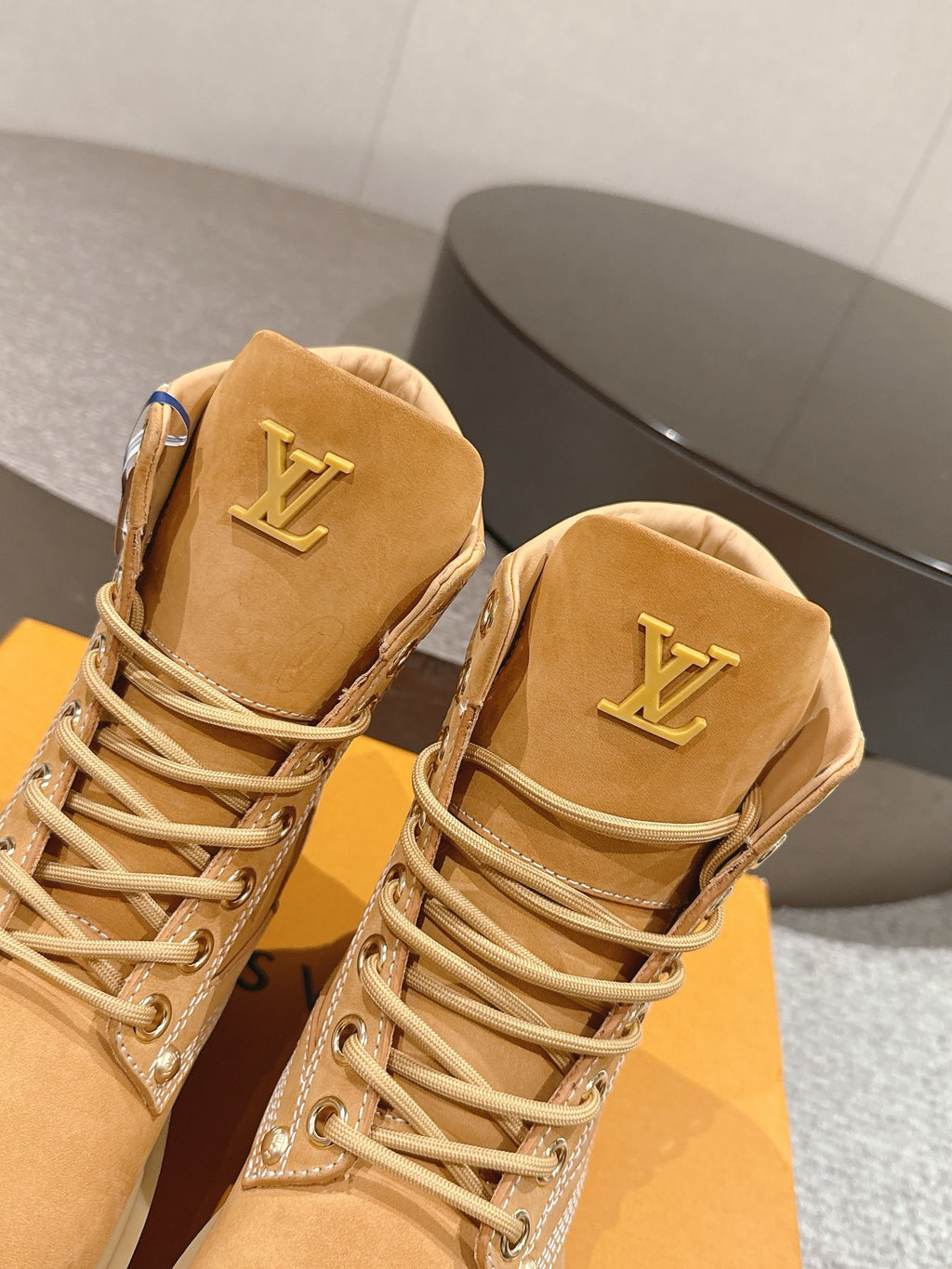 Close-up of tan lace-up ankle boots with LV logo on heel tab and decorative trim