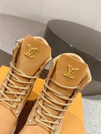 Close-up of tan lace-up ankle boots with LV logo on heel tab and decorative trim