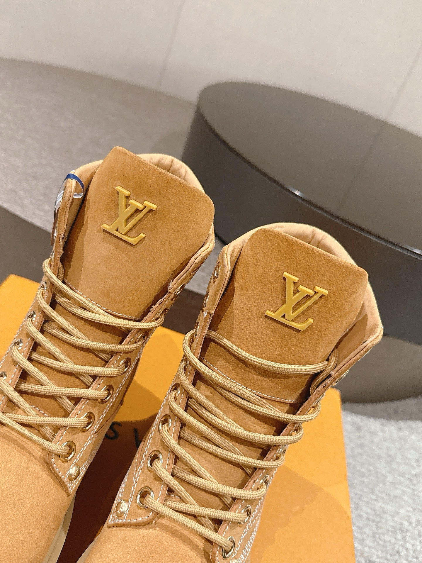 Close-up of tan lace-up ankle boots with LV logo on heel tab and decorative trim