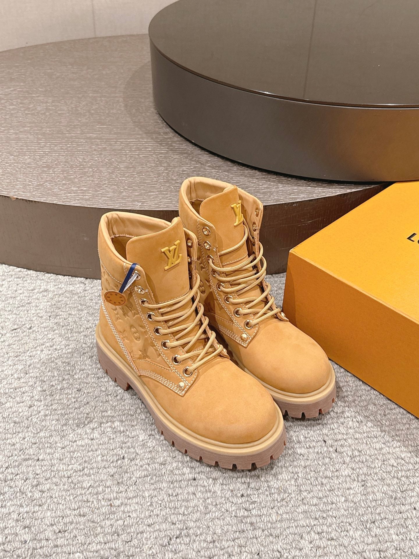 Tan suede lace-up ankle boots, angled view, with LV logo patches and chunky sole
