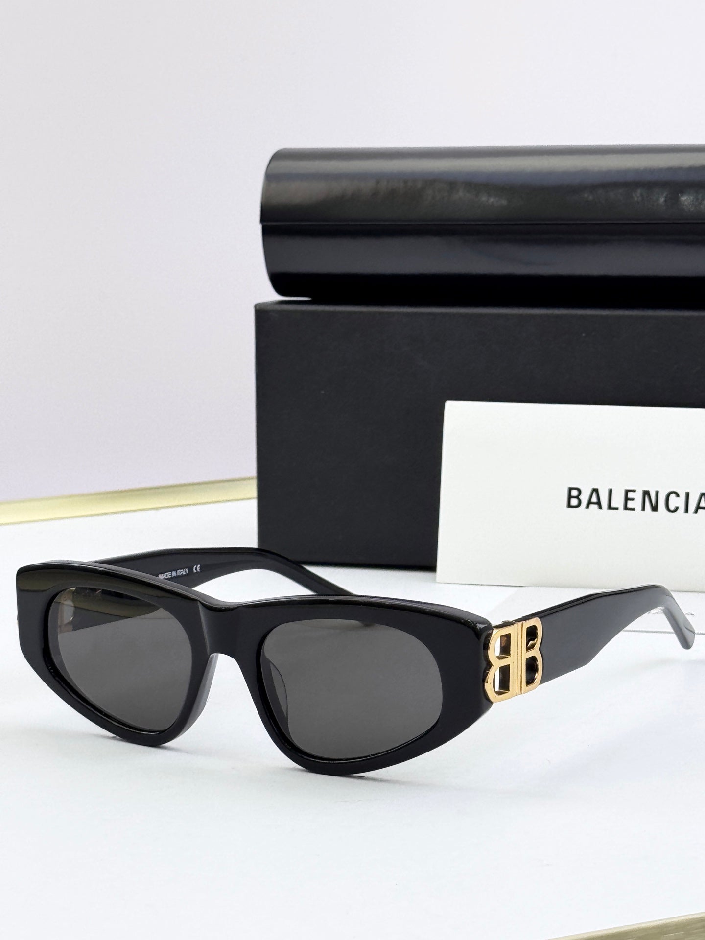 Black cat-eye sunglasses with dark lenses and gold B logo on temples