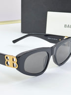 Matte black cat-eye sunglasses with dark lenses and gold B logo at temple