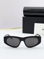 Black oversized sunglasses with dark lenses and gold-tone details at temples