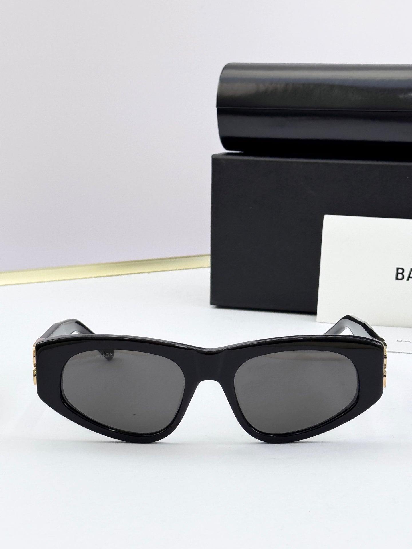 Black oversized sunglasses with dark lenses and gold-tone details at temples