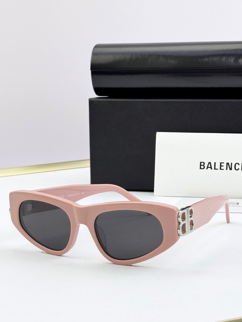 Blush pink cat-eye sunglasses with dark lenses and gold B logo on temples