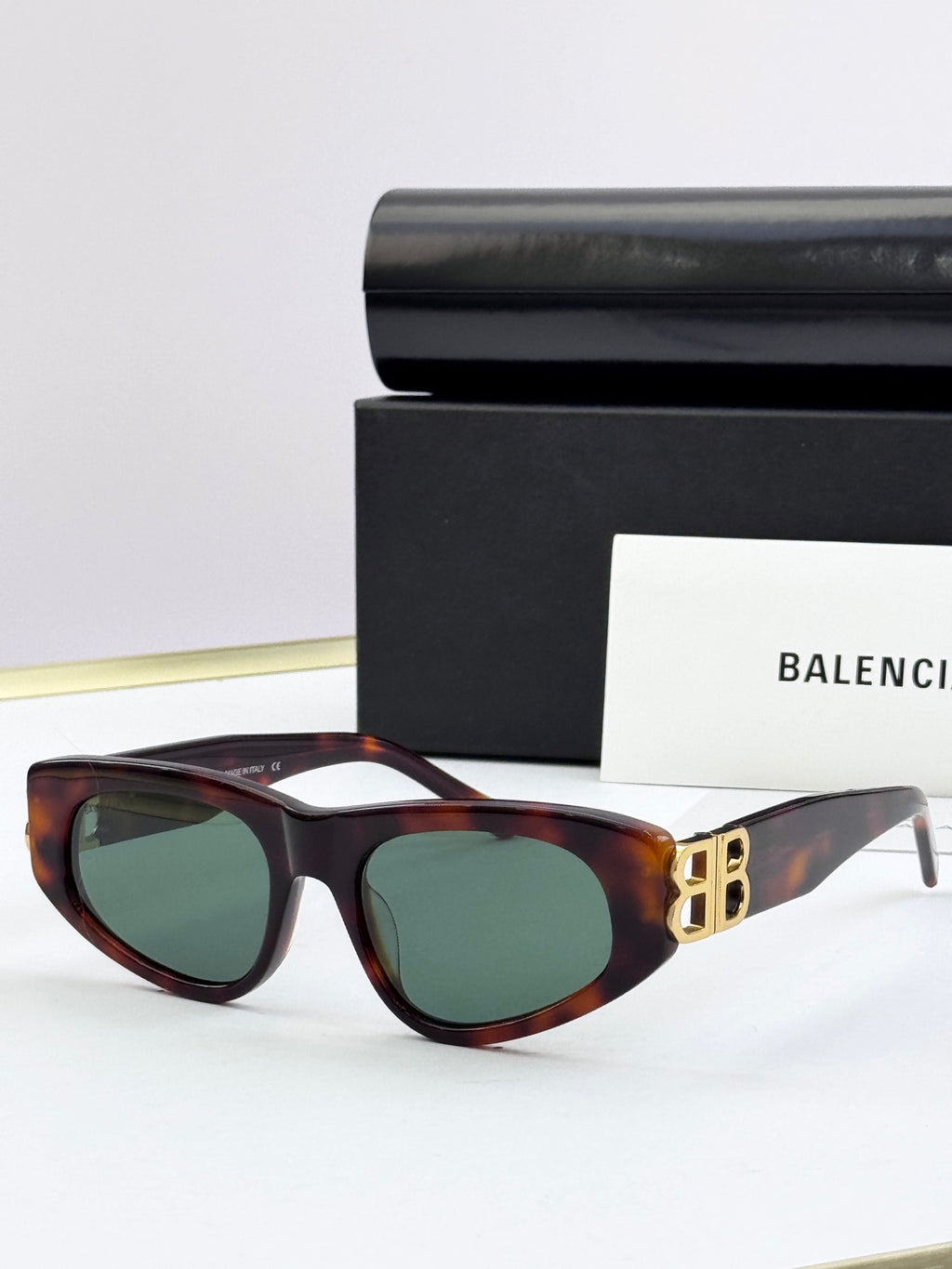 Tortoiseshell cat-eye sunglasses with green-tinted lenses and gold B logo