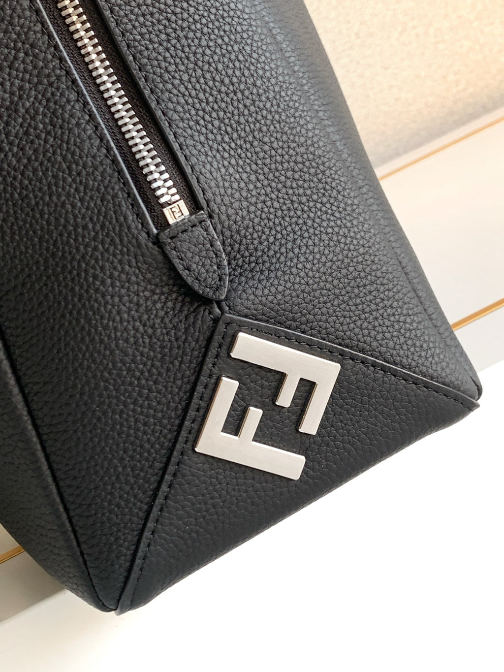 Black leather bag corner with metal F logo plate and silver zipper hardware