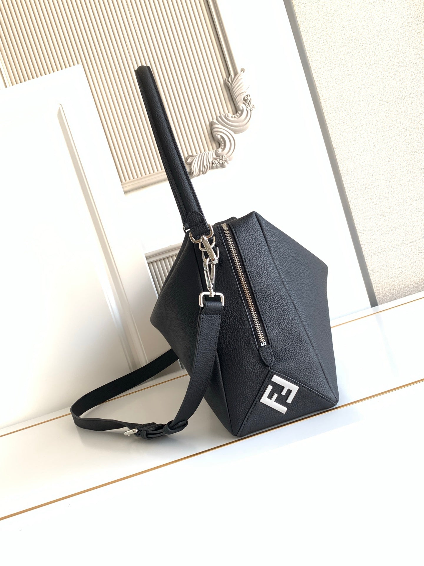 Black leather mini handbag with zip top, chain strap, and front logo plaque