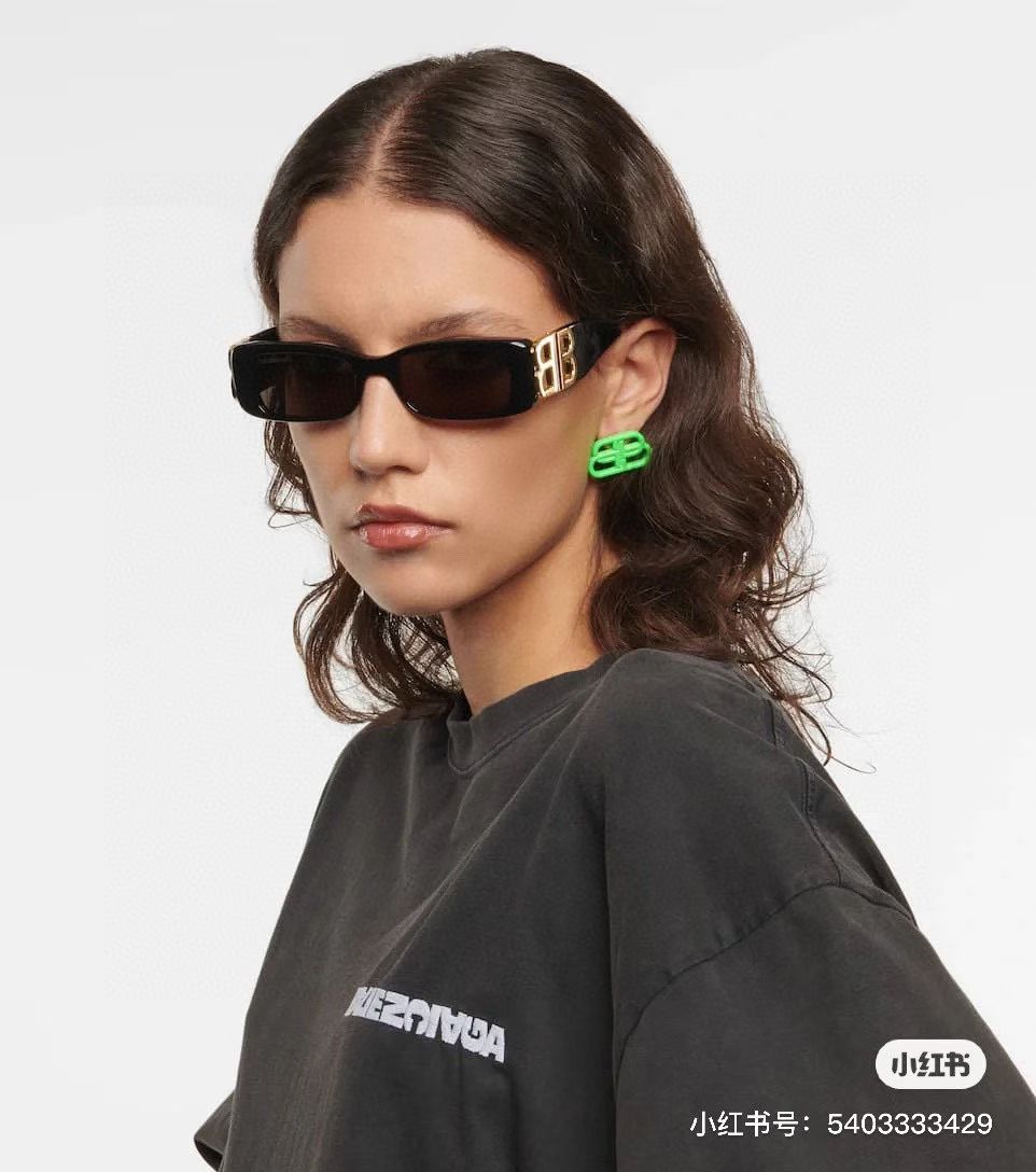 Balenciaga sunglasses with black frames and gold B logo temples, worn by model