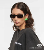 Balenciaga sunglasses with black frames and gold B logo temples, worn by model