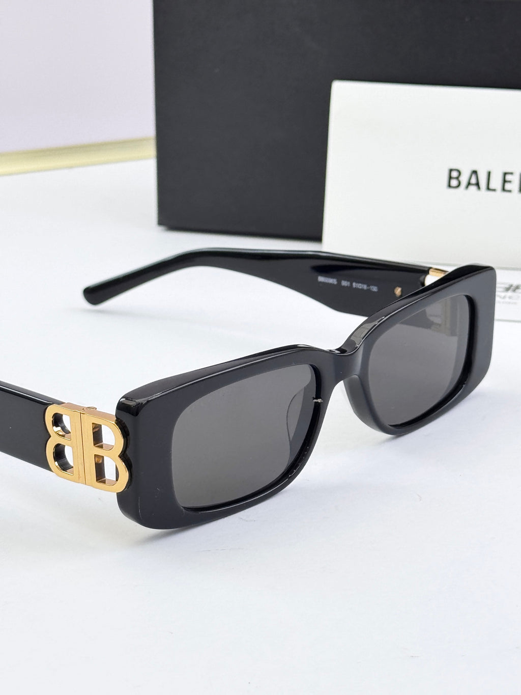 Balenciaga sunglasses, black frames with gold B logo hinge, dark lenses