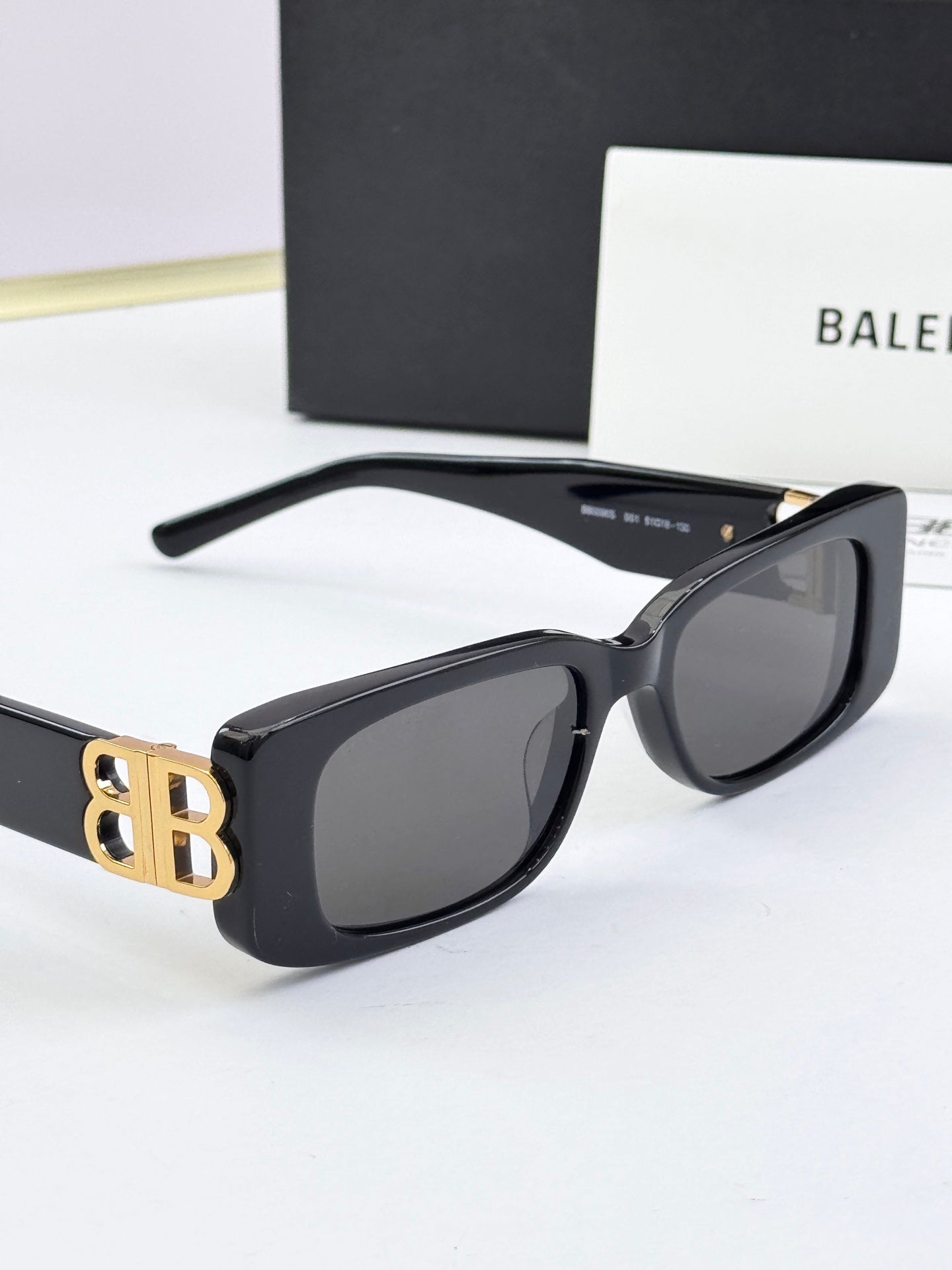 Balenciaga sunglasses, black frames with gold B logo hinge, dark lenses
