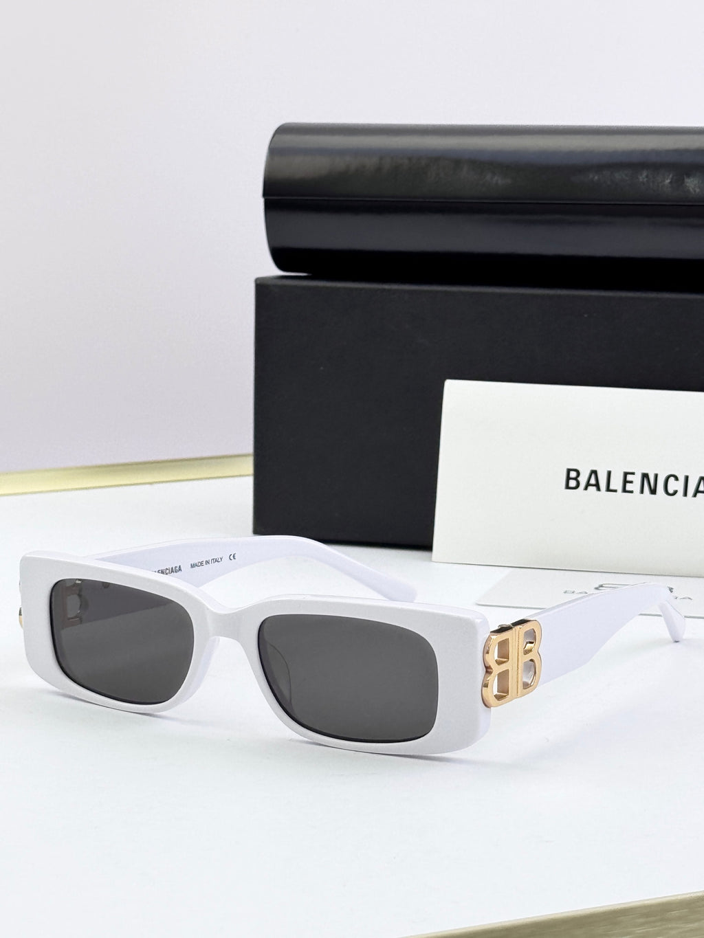 Balenciaga sunglasses with white frames, gold B logo temples, dark lenses