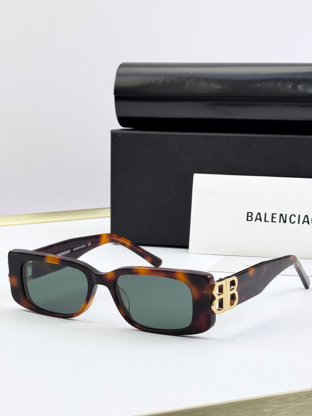 Balenciaga sunglasses with tortoiseshell frames, gold B logo temples, dark lenses