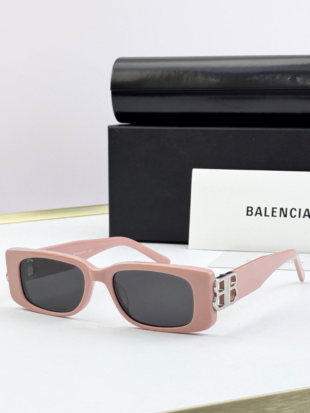 Balenciaga sunglasses with blush pink frames, gold B logo temples, dark lenses