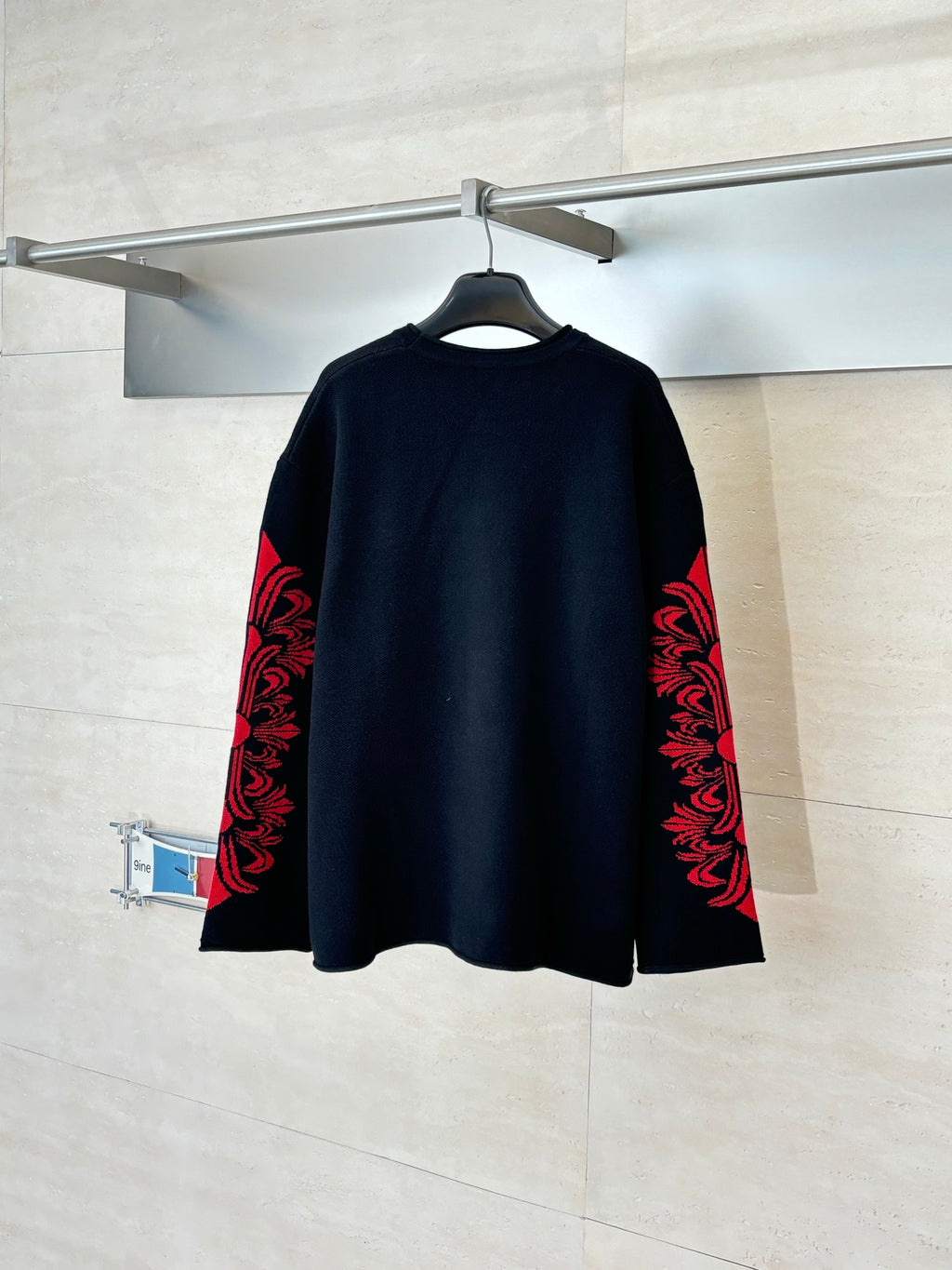 Black long-sleeve top with red ornate designs on both sleeves