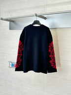 Black long-sleeve top with red ornate designs on both sleeves