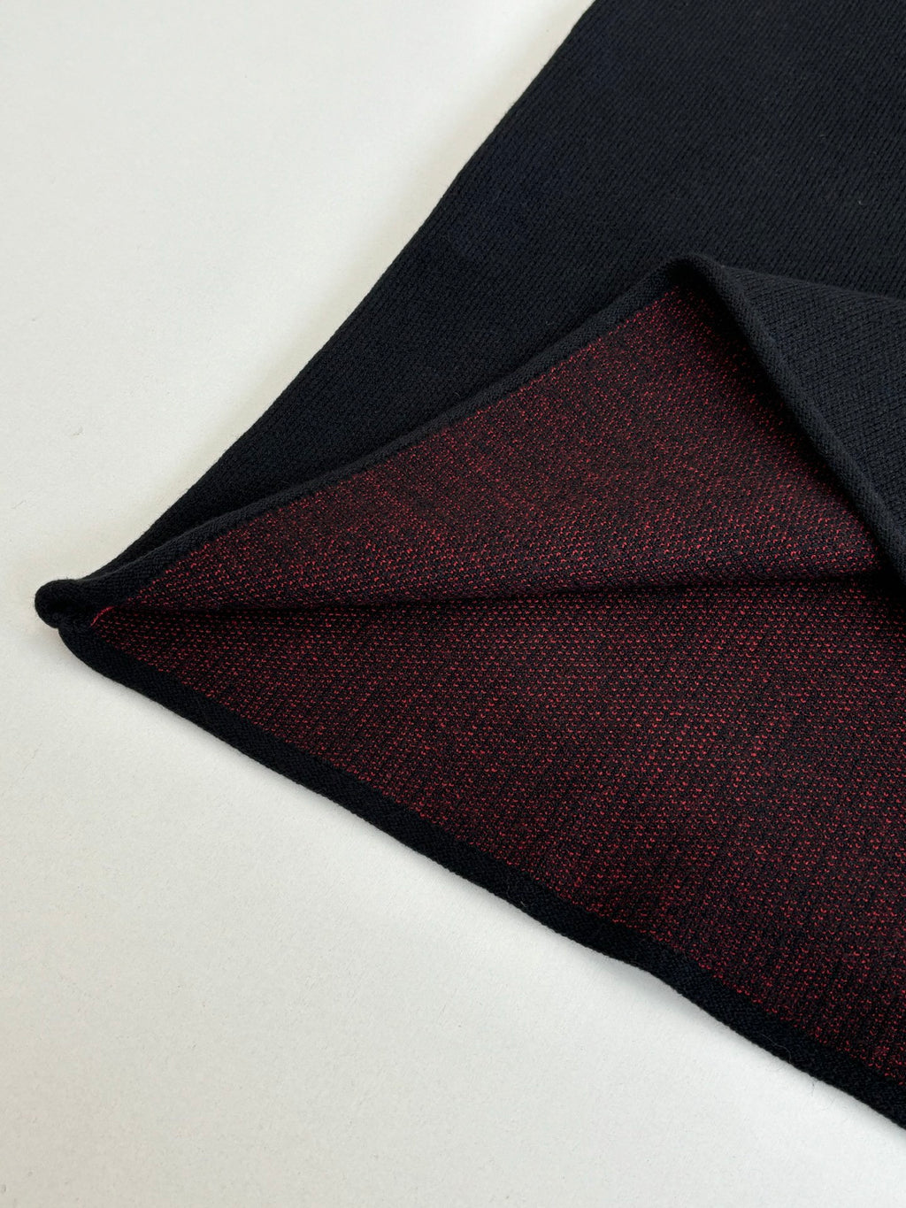 Black long-sleeve top showing dark red knit interior hem panel