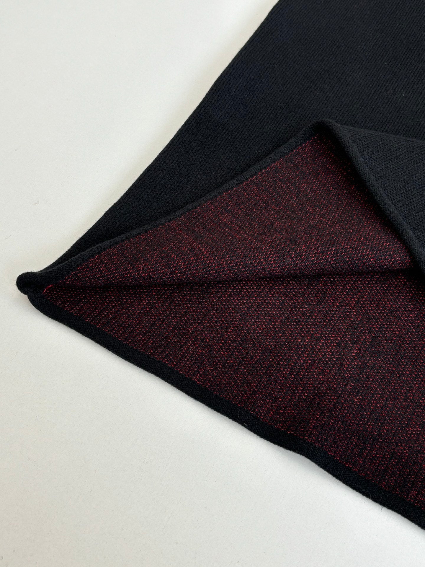 Black long-sleeve top showing dark red knit interior hem panel
