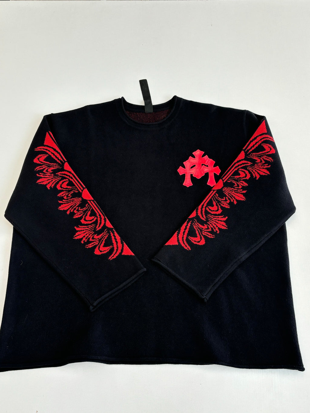 Black long-sleeve top with red cross and floral-style chest graphic