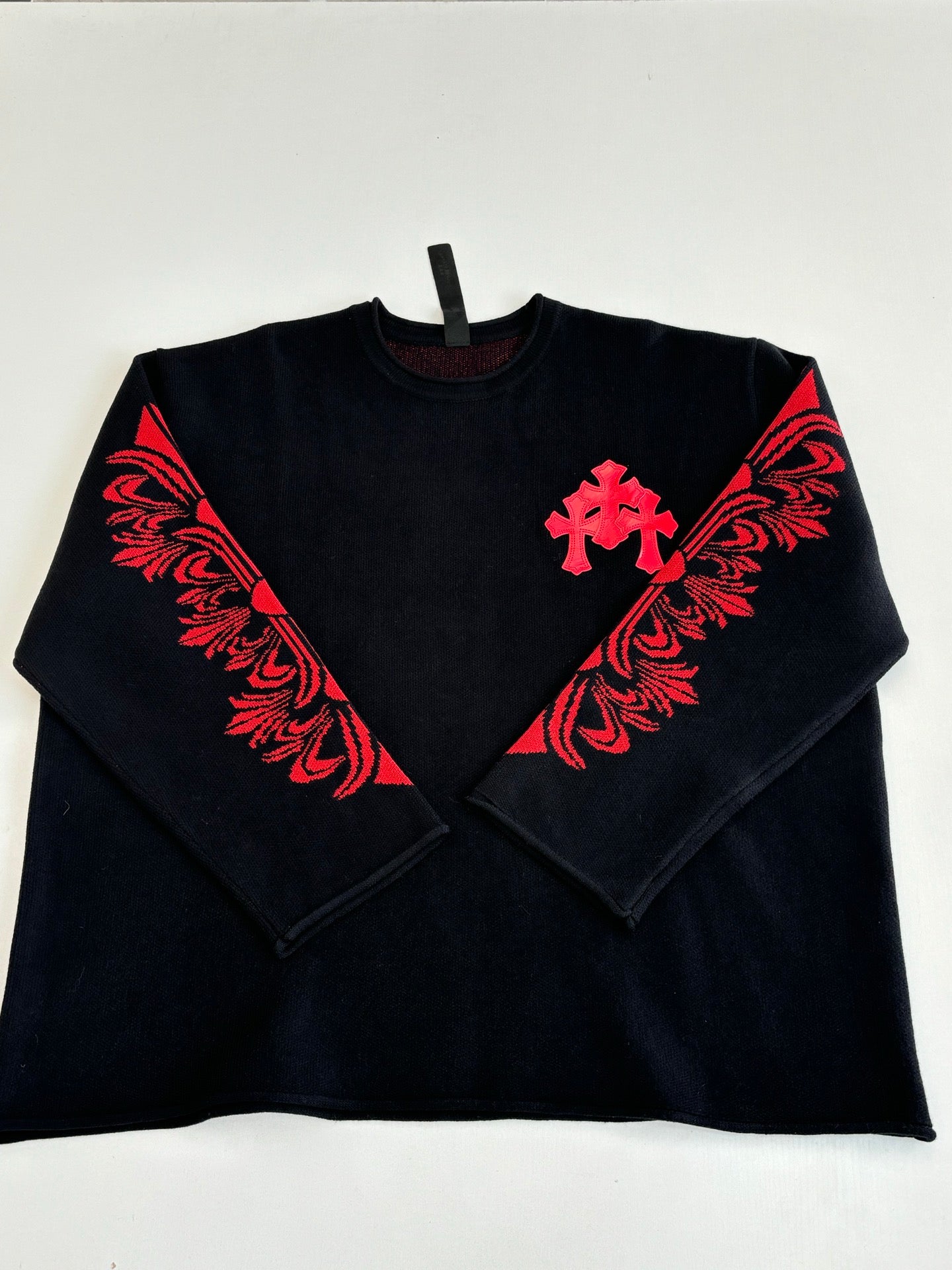Black long-sleeve top with red cross and floral-style chest graphic