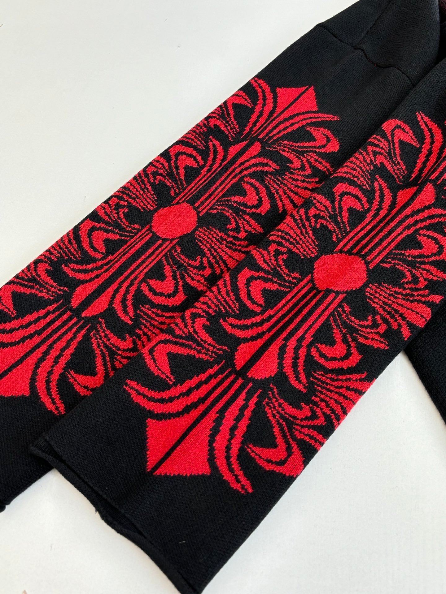 Black long-sleeve top with red ornate sleeve panel graphic