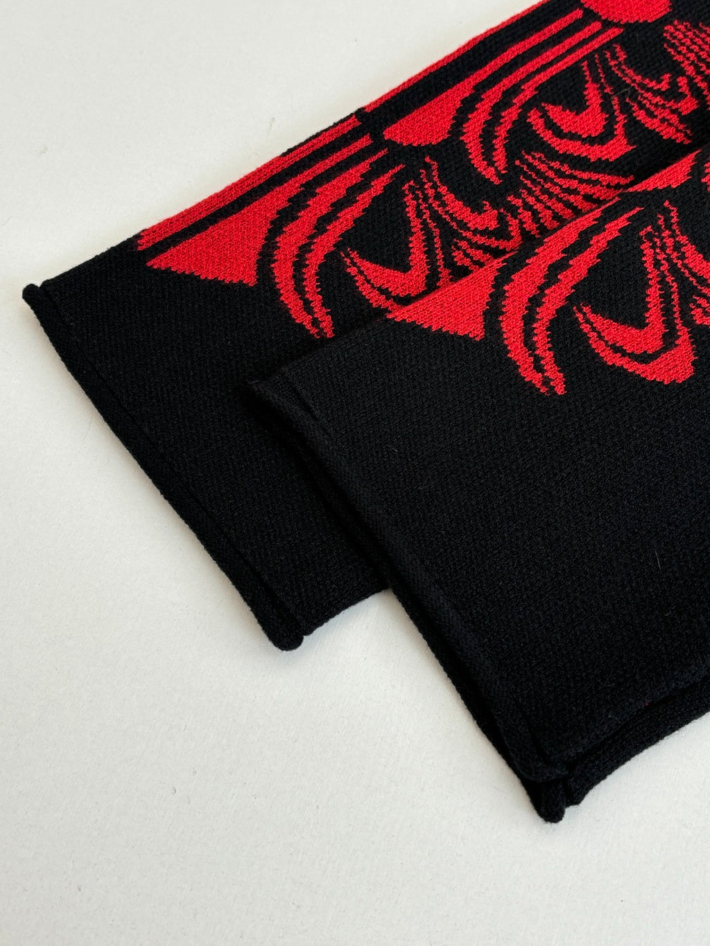 Black long-sleeve top with red ornate cuff stripe detail