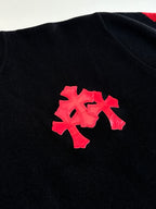Black long-sleeve top with small red cross patch on chest