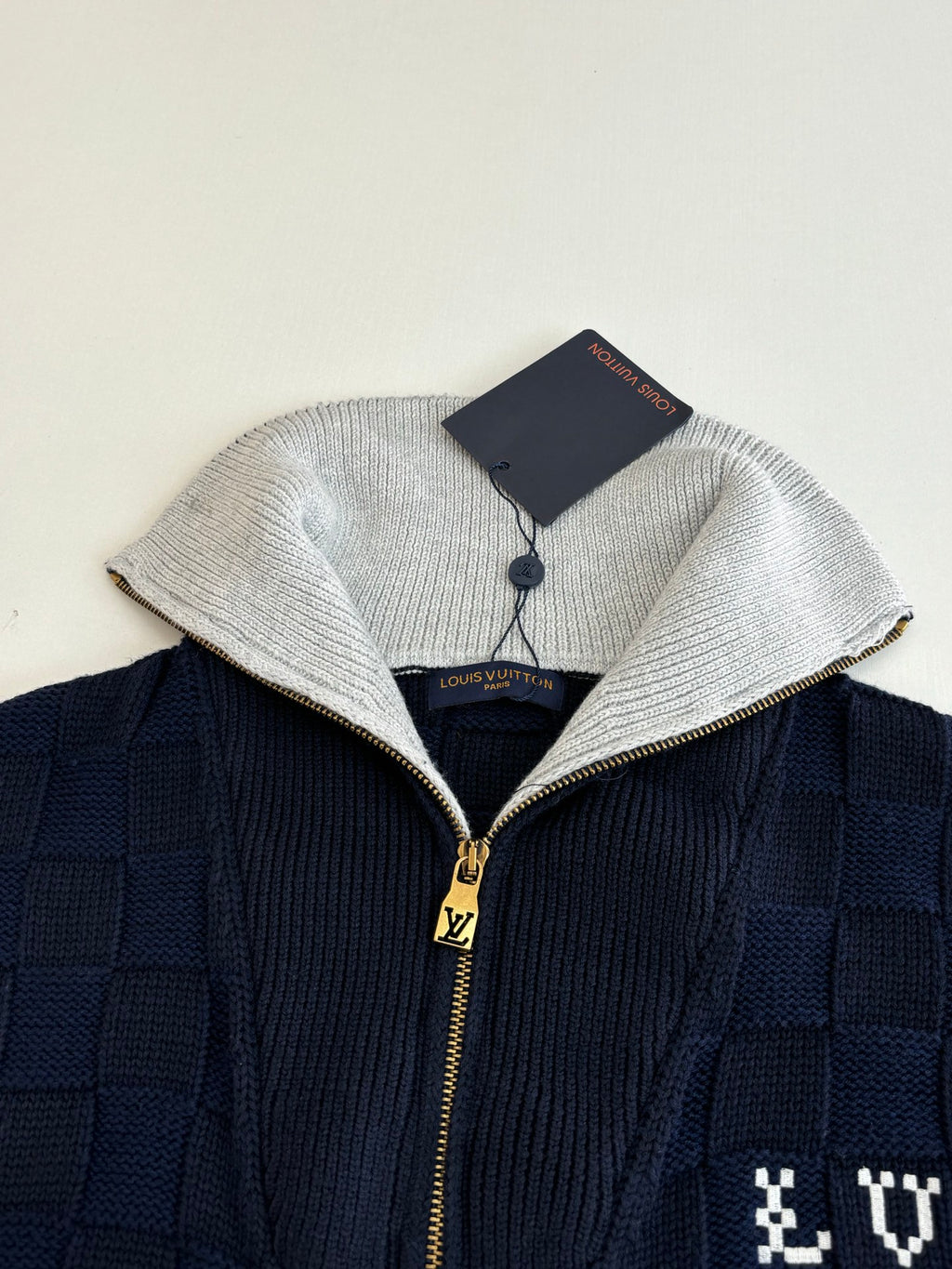 Louis Vuitton navy knit jacket close-up with silver hood trim and gold zipper