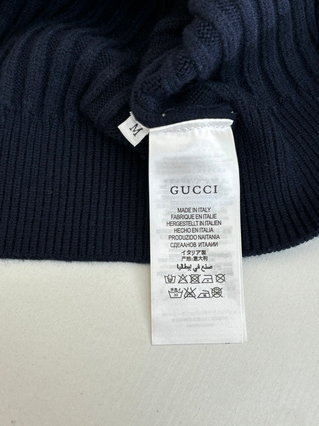 Interior care label on navy knit sweater, Gucci and made in Italy